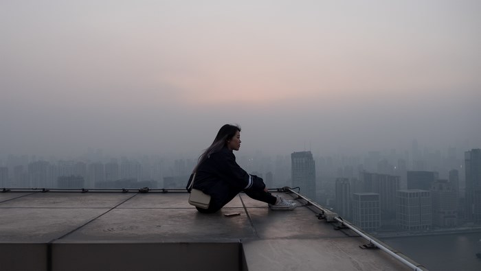 Woman sitting on a rooftop overlooking Shanghai