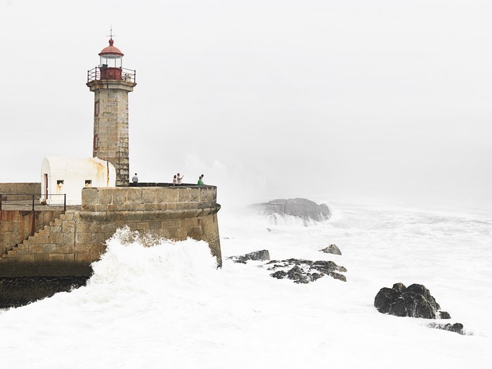 Lighthouse on a stone pier with crashing waves