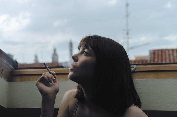 Woman smoking a cigarette on a rooftop