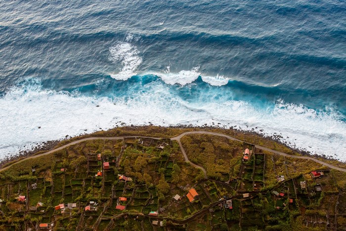 Aerial view of houses and waves crashing on the shore