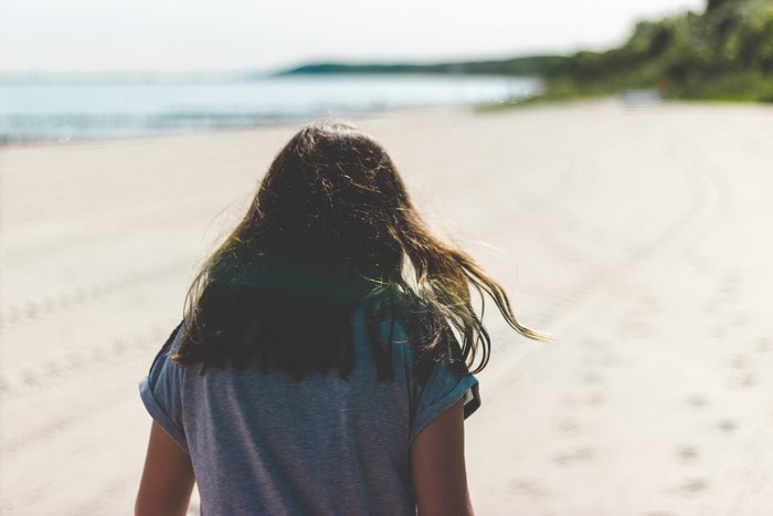 Woman walking on a sandy beach by the sea