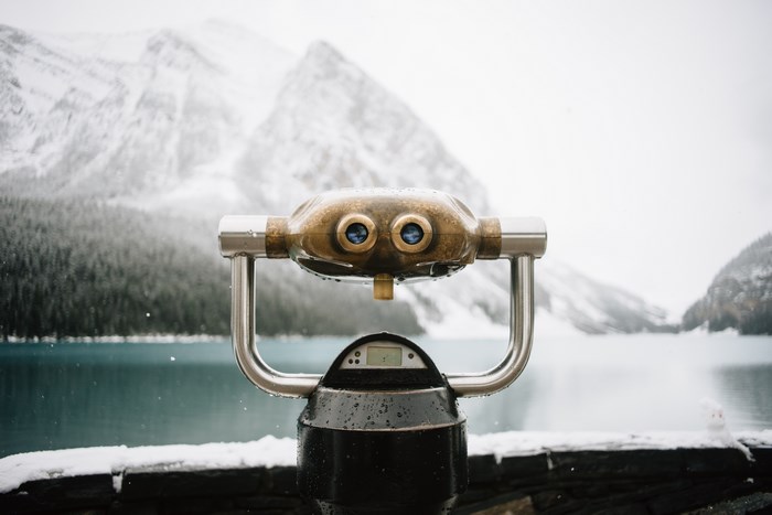 Binocular viewer overlooking a snowy mountain lake in Banff