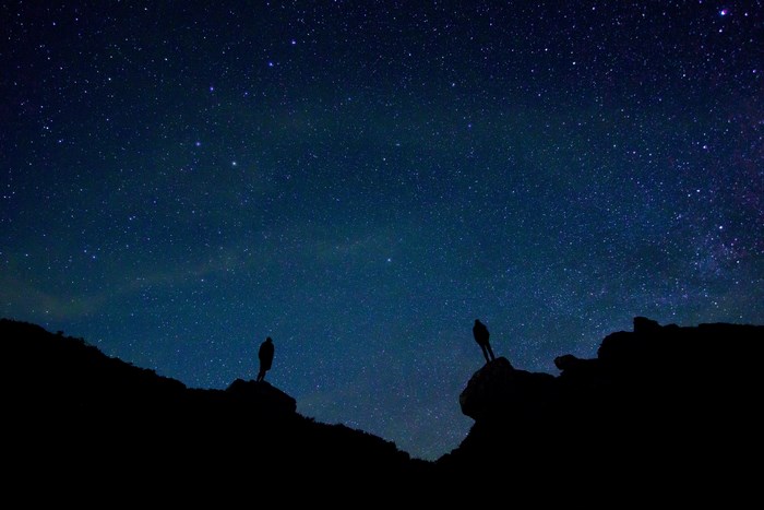 Two people silhouetted against a starry night sky
