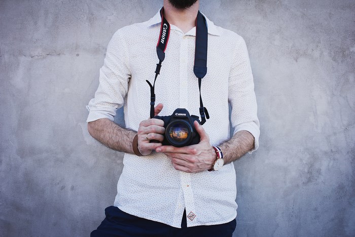 Man holding a Canon camera with a Canon strap