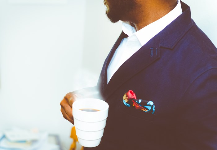 Man in suit holding a cup of coffee
