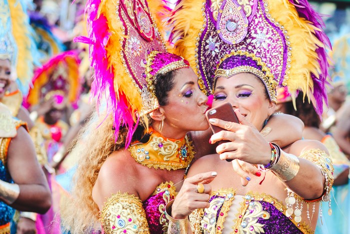 Two women in colorful costumes taking a selfie at a festival