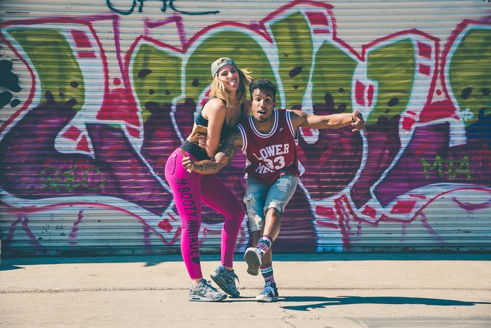 Woman and man posing in front of graffiti