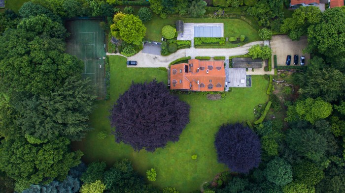 Aerial view of a house with a pool and tennis court in Brussels