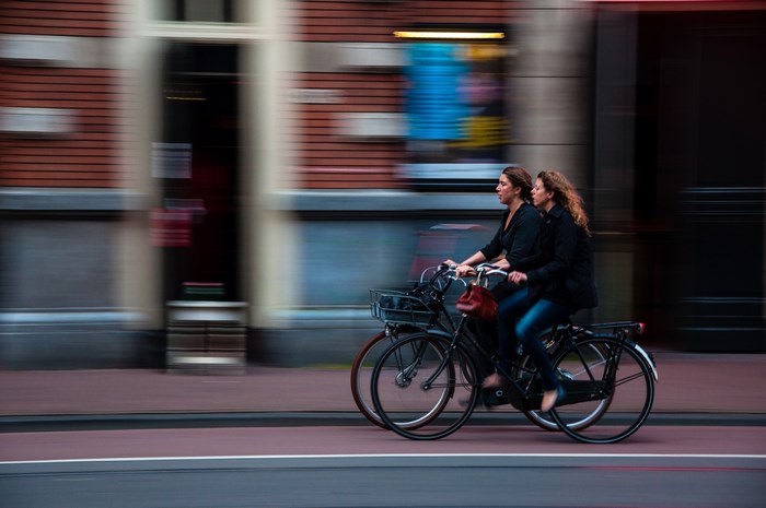 Two women riding bicycles in a city