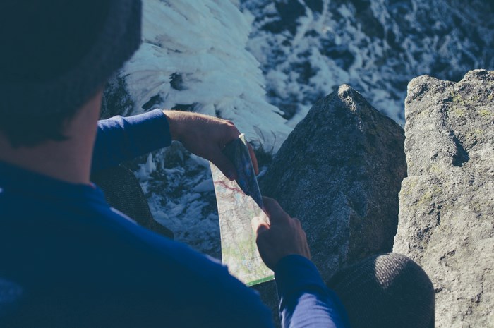 Man looking at a map on a rocky mountain with snow