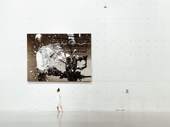 Woman in white dress looking at abstract art in a gallery