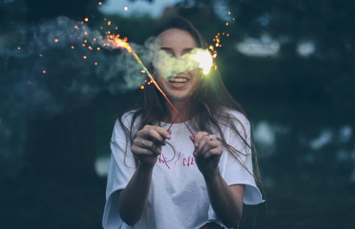 Woman smiling while holding sparklers at night