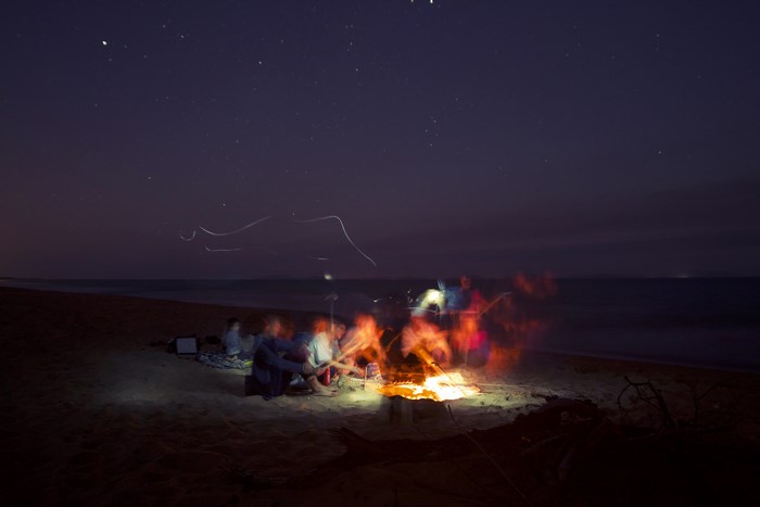 People around a bonfire on a beach at night