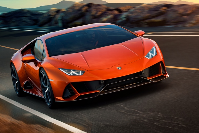 Orange Lamborghini Huracan Evo driving on a road