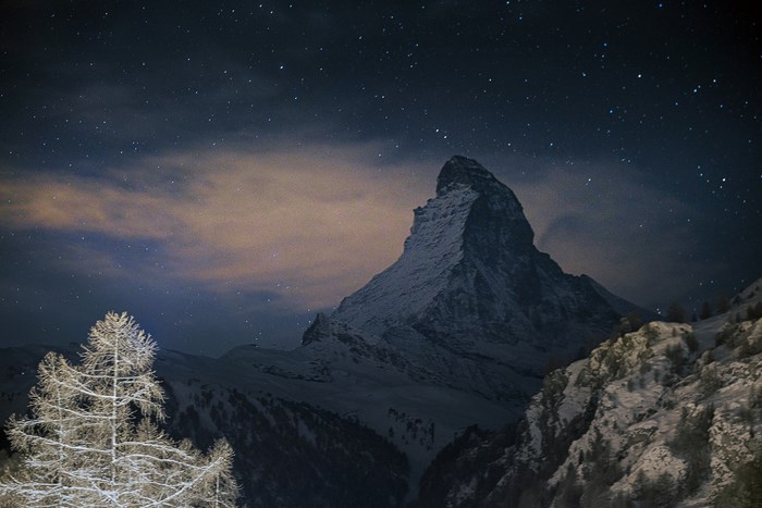 Matterhorn mountain at night with stars and clouds