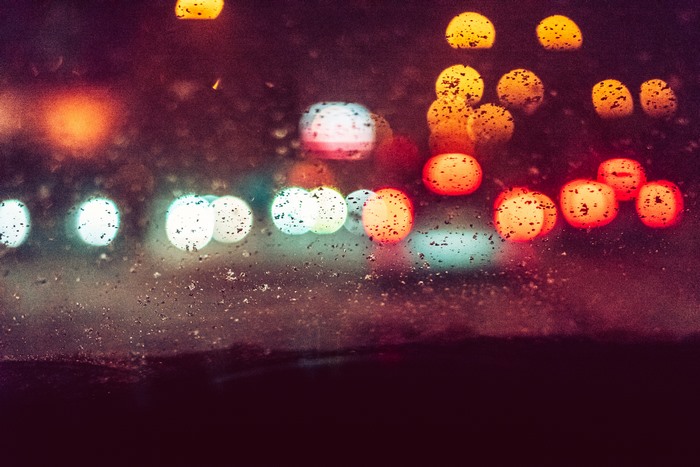 Bokeh effect of city lights at night through a wet window