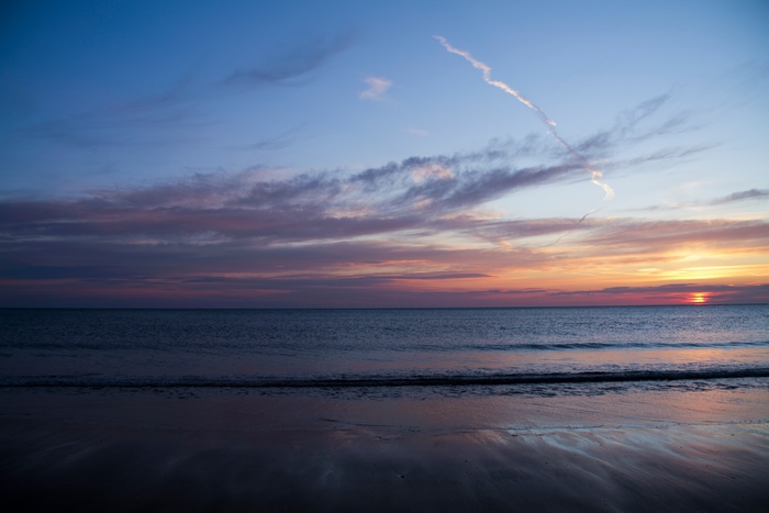 Sunset over the ocean with clouds and beach