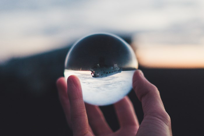 Hand holding a crystal ball with a plane wreck inside