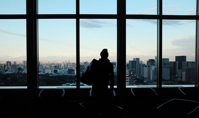 Silhouette of a person with a backpack looking out at a city skyline