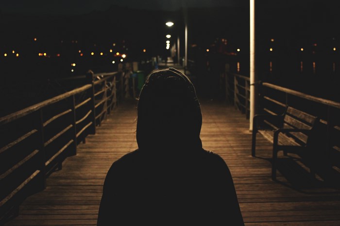 Silhouette of a person on a boardwalk at night