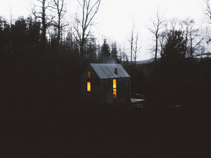 Remote cabin in a dark forest at dusk