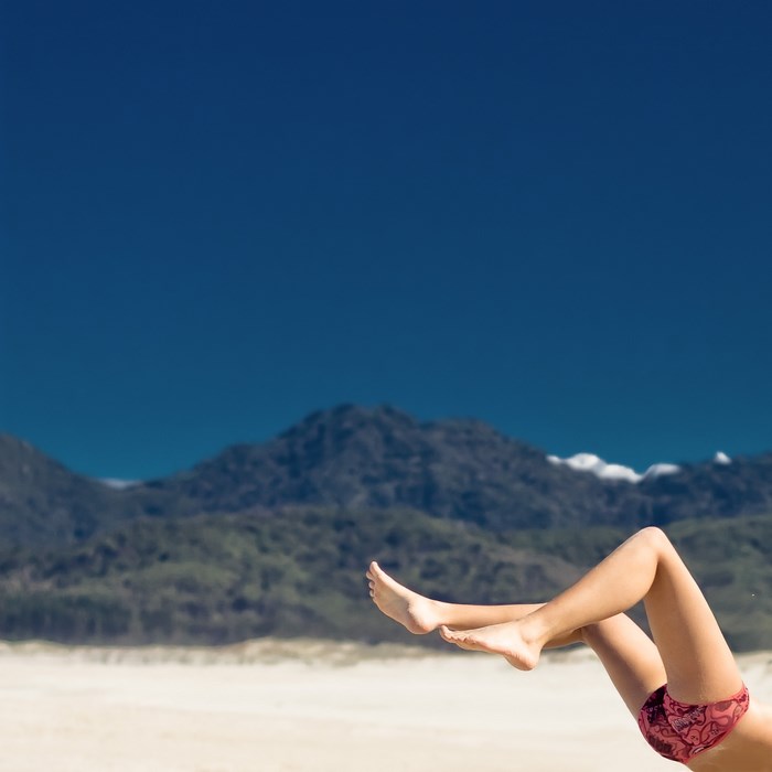 Woman's legs on a beach with mountains