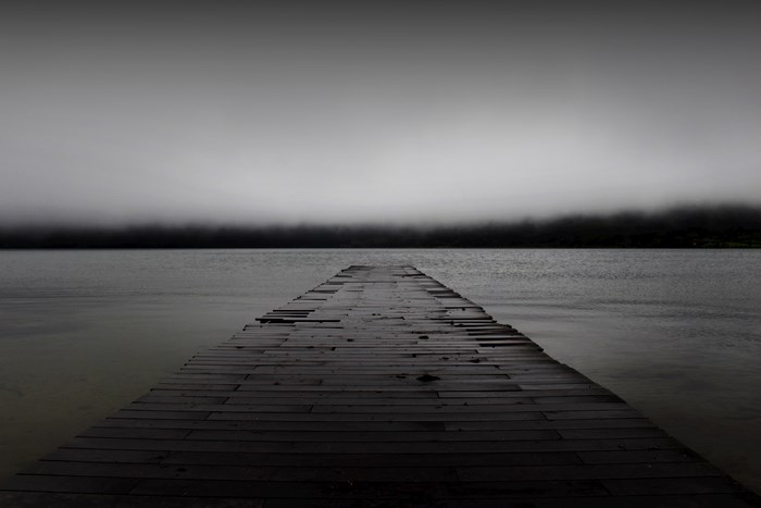 Wooden pier on a foggy lake at dusk