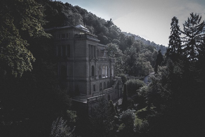 Old manor house nestled in a dense forest on a hillside