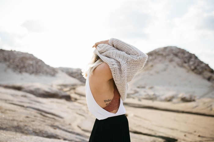 Woman in sweater and black skirt with tattoo
