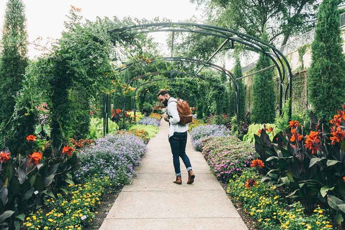 Man with backpack walking through a colorful garden