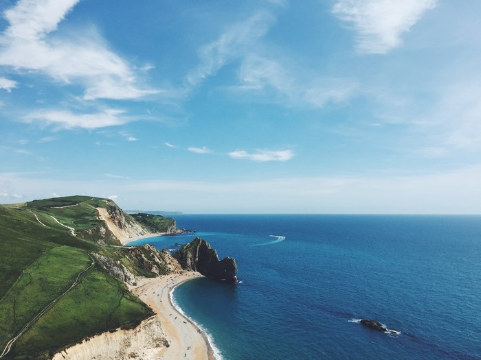 Green cliffs meet the blue ocean and sandy beach