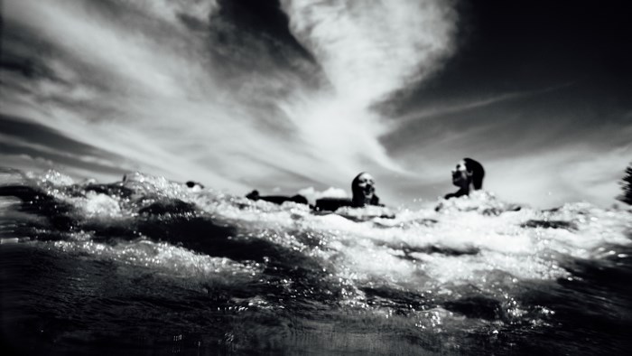 People swimming in the ocean under a cloudy sky