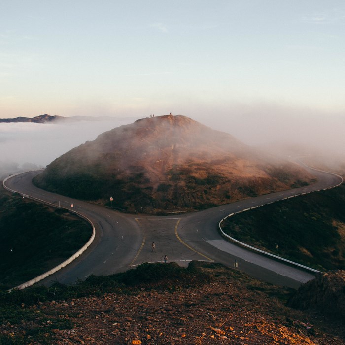 Road splitting on a foggy mountain with people on top