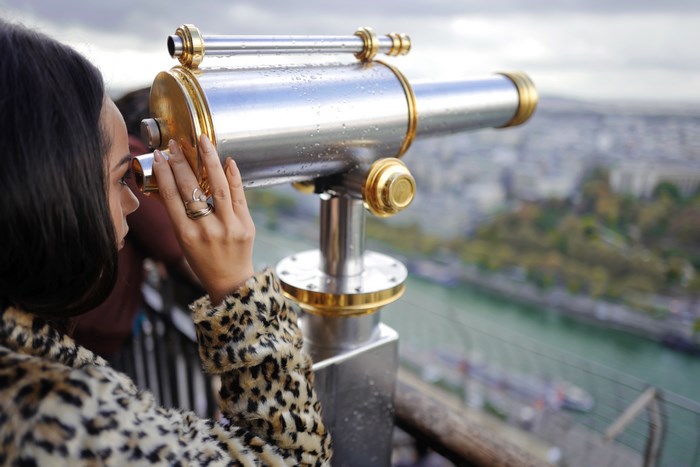 Woman looking through a telescope at a river overlook