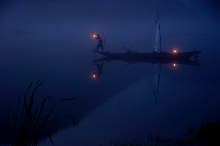 Man with lantern on a boat at night