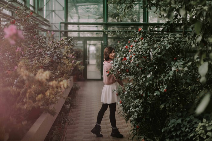 Woman in a pink sweater and white skirt in a greenhouse