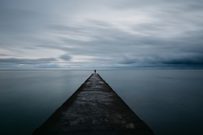 Person standing on a pier overlooking the ocean