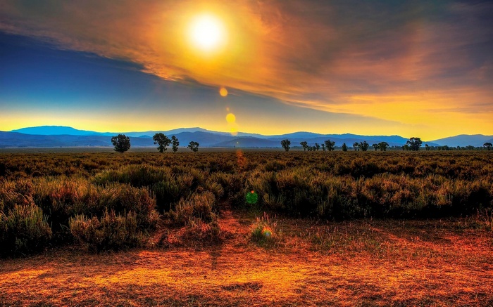 Sunset over a field with mountains in the distance