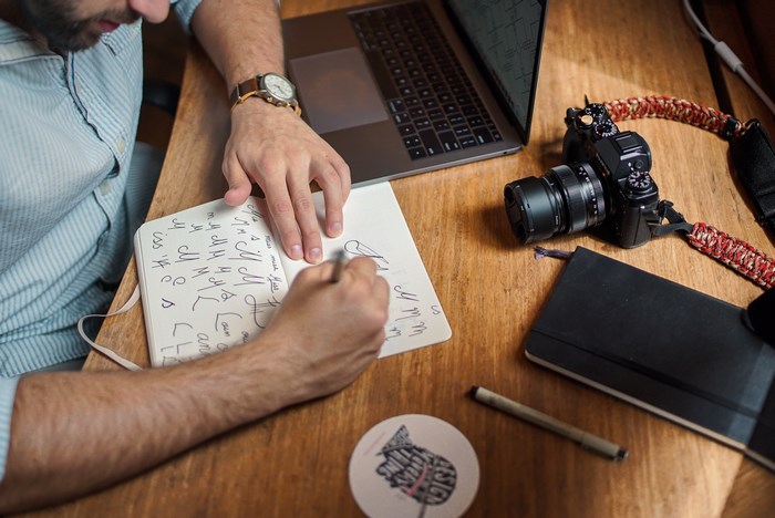 Man Working on Design Sketches with Camera and Laptop