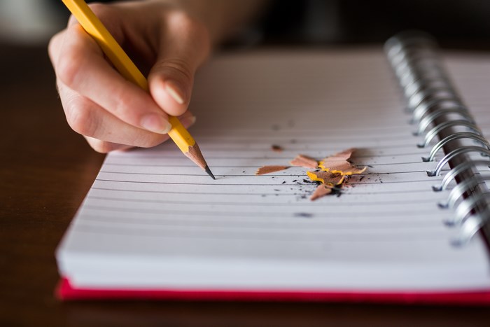 Hand writing with a pencil on a notebook