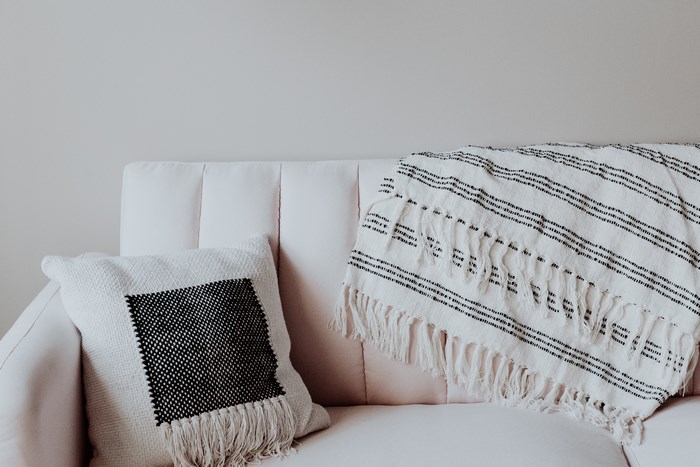 Cushion and blanket on a light pink sofa