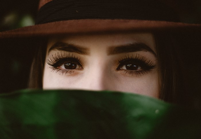 Woman wearing a hat and hiding behind a leaf