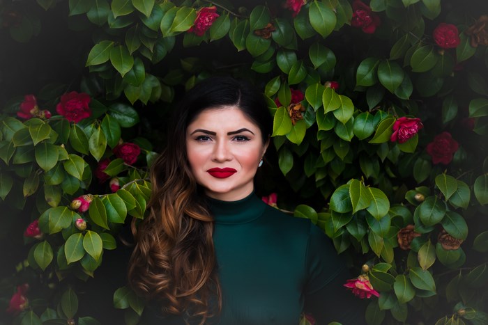 Woman with red lips in front of green foliage