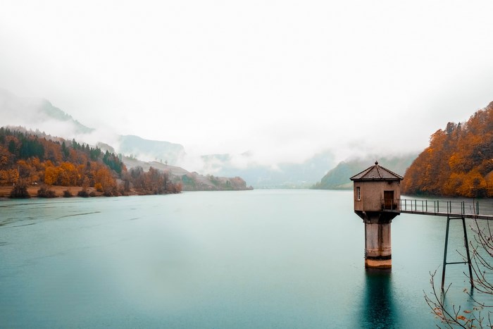 Tower in a lake with misty mountains and autumn trees