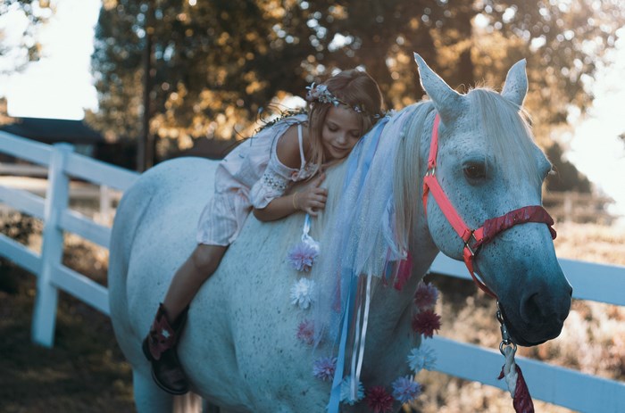 Girl with flower crown on a decorated white horse