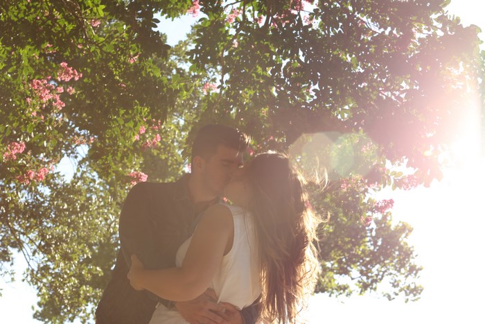 Couple Embracing and Kissing Under Sunlit Trees