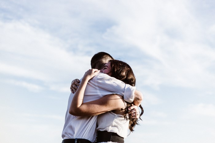 Couple embracing outdoors against a cloudy sky