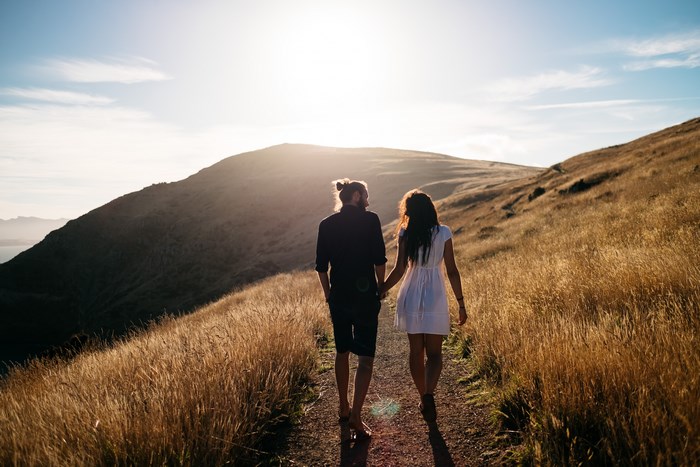 Couple walking on a mountain trail at sunset