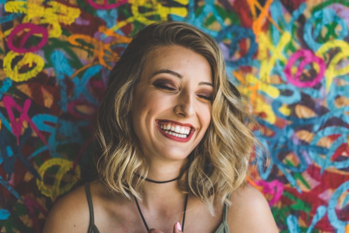 Woman laughing in front of colorful graffiti wall