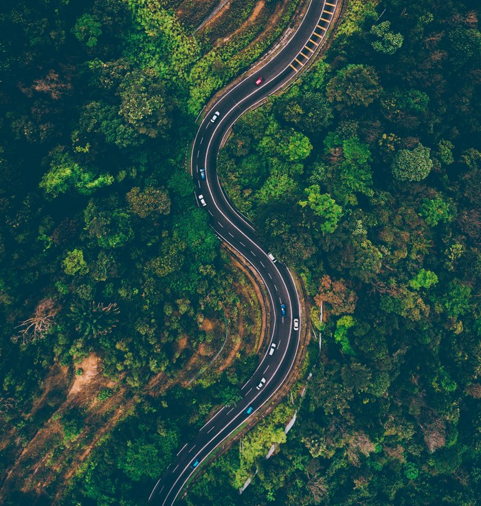 Aerial view of a winding road through a dense forest